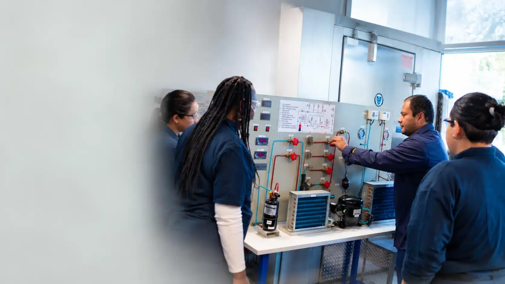 HVAC students working on refrigeration equipment in a training lab